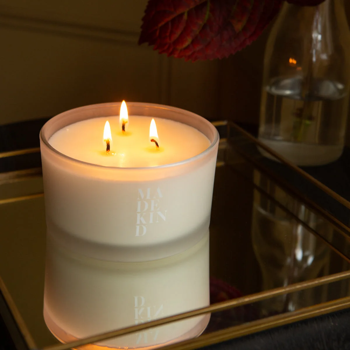 Photo of a large 3 wick candle in a frosted glass container with MadeKind logo, on a mirrored tray.