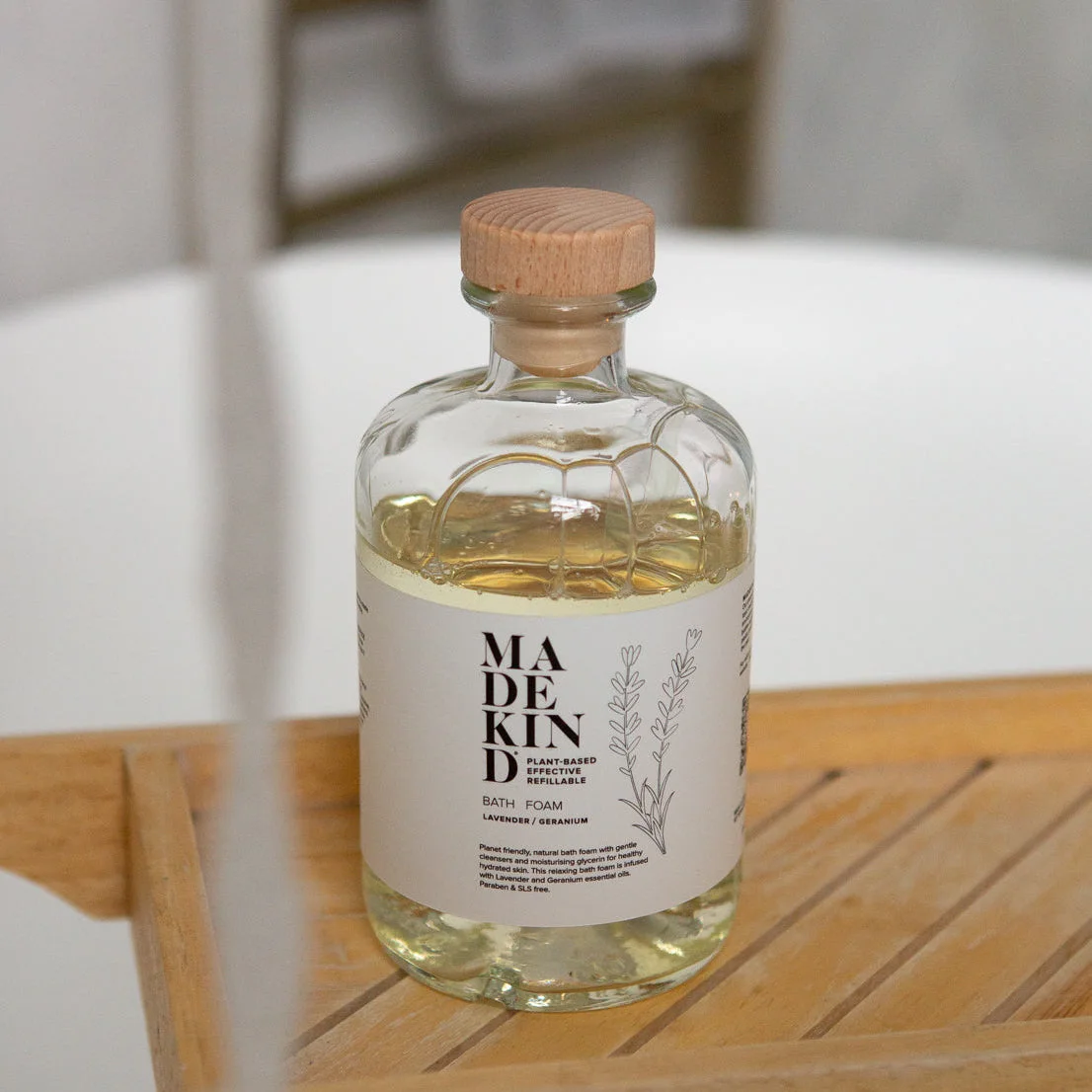Bottle of Madekind Bubble bath on a wooden surface with a blurred background in a bathroom