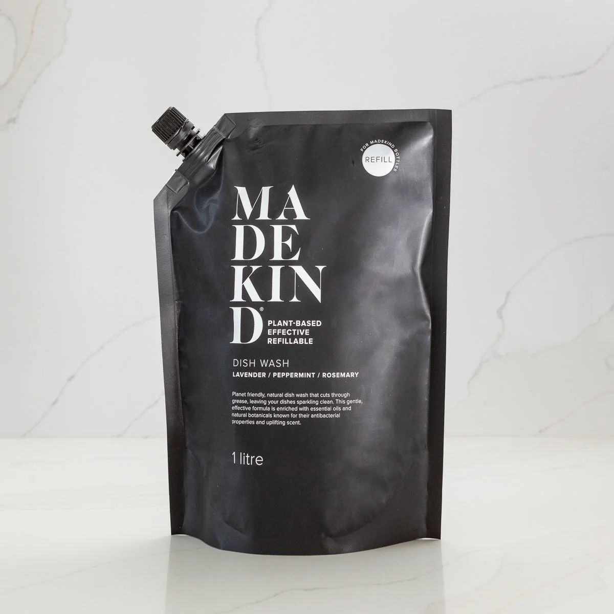 Black sustainable refill pouch with 'MadeKind' branding on a white kitchen background